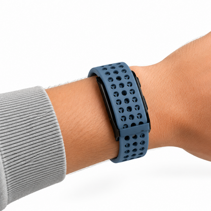 Bracelet RYTM en silicone perforé bleu marine porté au poignet, sous une manche de sweat gris.