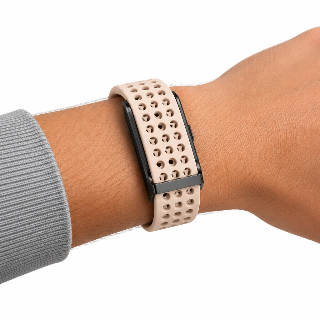 Bracelet RYTM en silicone perforé rose poudré porté au poignet, sous une manche de sweat gris.